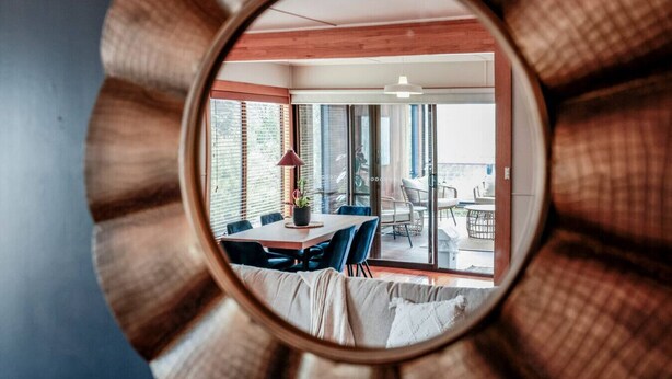 Ein Zimmer mit großem Fenster, einem Essbereich mit Tisch und Stühlen und Blick ins Freie.