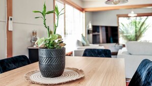 Ein modernes Wohnzimmer mit einem Holzesstisch, einer Topfpflanze und einem Sofa.