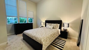 A bedroom with a bed, two bedside tables, a window, and a view of greenery outside. - Charming townhome with AC in Hillsboro (Hillsboro)