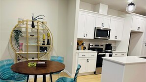 A modern kitchen with white cabinets, a microwave, and a stove. There is a dining area with a round table and chairs. - Charming townhome with AC in Hillsboro (Hillsboro)