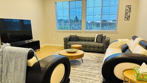 A modern living room with a sofa, a coffee table, and a TV. - Charming townhome with AC in Hillsboro (Hillsboro)