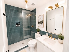 A bathroom with a glass-enclosed shower, a white toilet, a sink with gold fixtures, and a mirror with a gold frame. - Luxury Mountain Townhome Steps to Government Camp, Ski Bowl, Pool & Hot Tub (Government Camp)