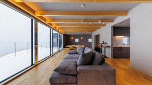 Un interno moderno con soffitto in legno, un'ampia finestra, un divano componibile e un angolo cottura.
