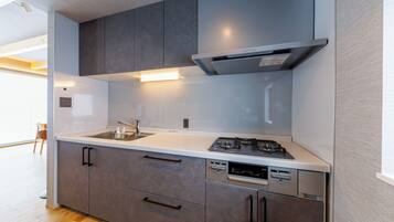 A modern kitchen with grey cabinets, a white countertop, a built-in dishwasher, and a gas stove.