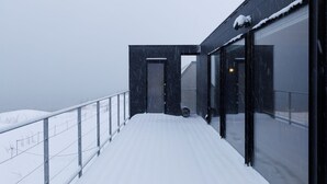 Un vialetto innevato che conduce a un edificio moderno con ampie finestre e ringhiera in metallo.