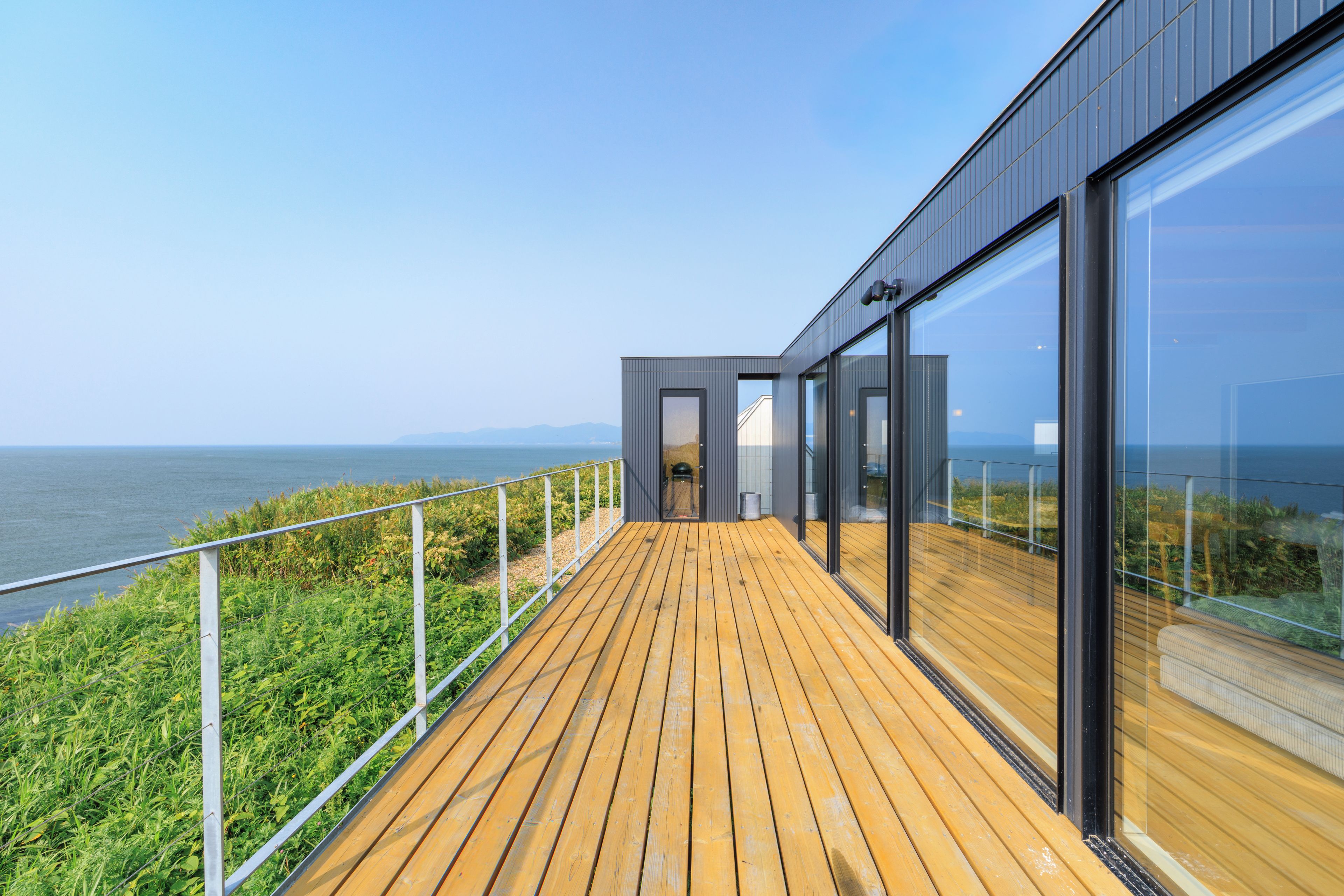 A modern building with a wooden deck overlooking a body of water.