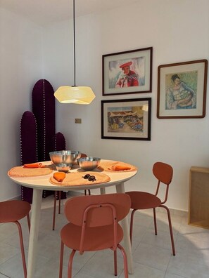 Un comedor con una mesa redonda, cuencos metálicos, individuales anaranjadas y sillas rojas.