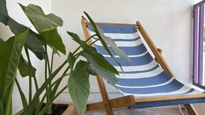 A wooden chair with a blue and white striped fabric, a potted plant, and a tiled floor. - Shelter among plants in Tampiquito 2br, 3bed, 2ba (San Pedro Garza García)