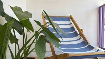 A wooden chair with a blue and white striped fabric, a potted plant, and a tiled floor.