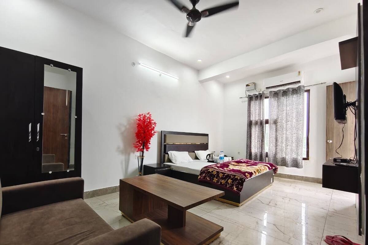 Una habitación de hotel moderna con cama, escritorio, silla, armario y televisor.