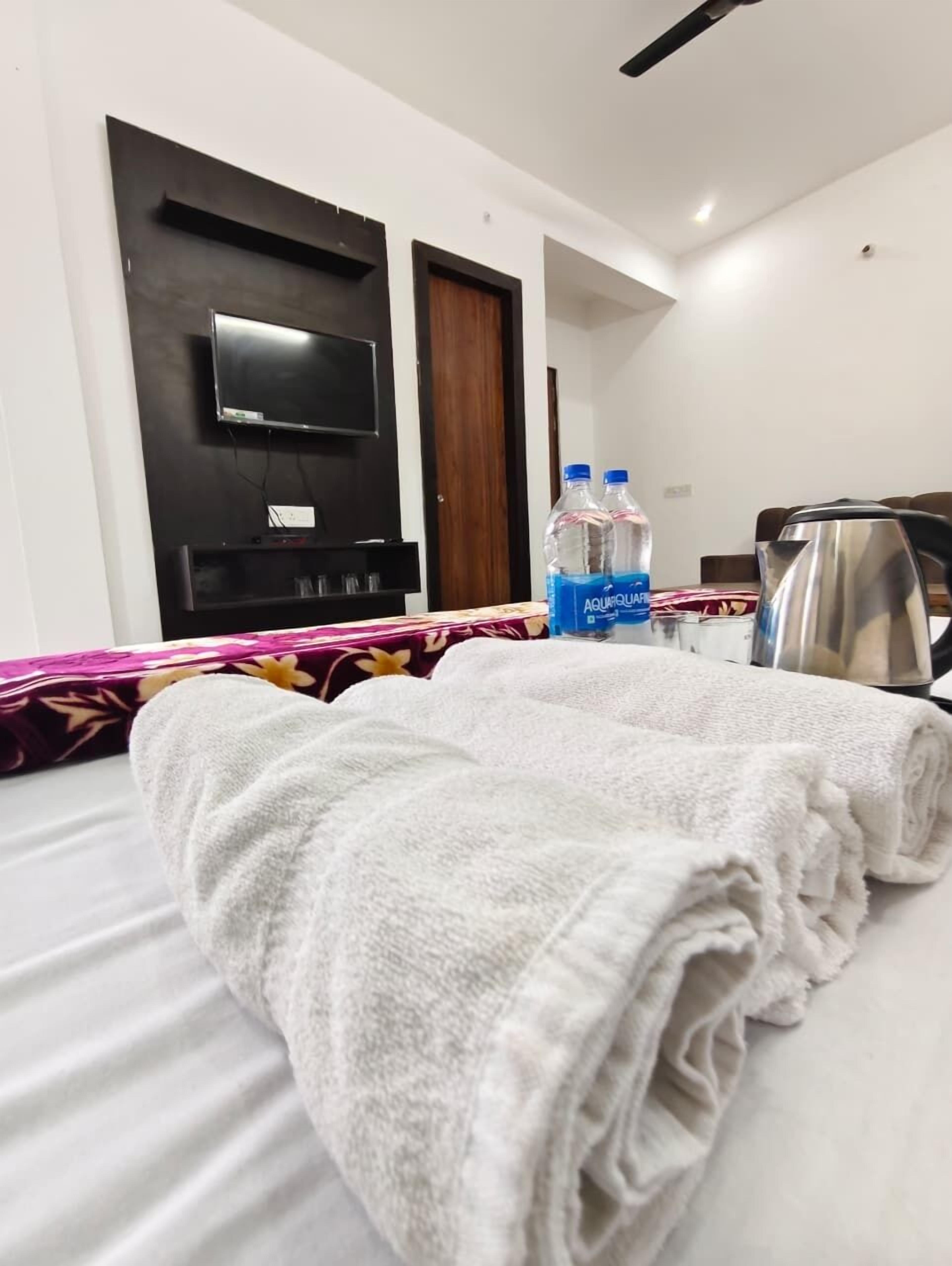 Hotelkamer met een bed, een flatscreen televisie aan de muur, een waterkoker en twee waterflessen.