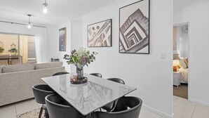 A modern living room with a dining area, featuring a marble table, black chairs, and a grey sofa. - Best Location Armadale Sleeps 6 (Perth)