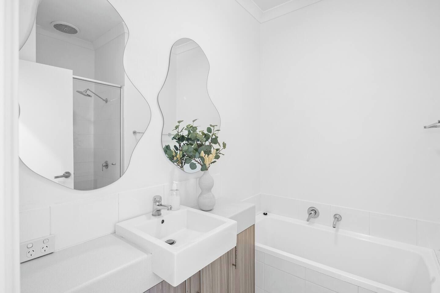 A modern bathroom with a large mirror, a sink, a shower, and a bathtub.