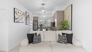 A modern living room with a sofa, two patterned cushions, and a dining area in the background. - Best Location Armadale Sleeps 6 (Perth)