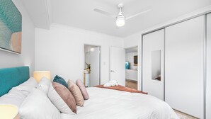 A bedroom with a bed, pillows, a nightstand, a ceiling fan, and a wardrobe. - Stylish 2BR With Wi-fi 100 Mbps TV big 75 Inch (Perth)
