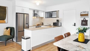A modern kitchen with white cabinetry, stainless steel appliances, and a marble countertop. - Stylish 2BR With Wi-fi 100 Mbps TV big 75 Inch (Perth)
