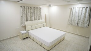 Une chambre à coucher avec un lit, une table de chevet, des rideaux et un ventilateur de plafond.