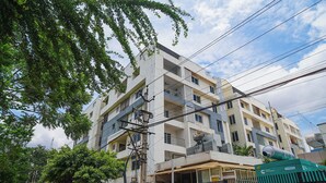Un immeuble résidentiel à plusieurs étages, doté de balcons, d’une entrée sécurisée et d’installations électriques apparentes.