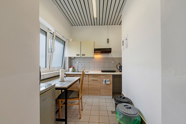 Cocina compacta con ventana, un lavamanos, estufa y zona de comedor con una silla y mesa.