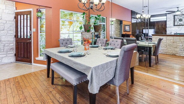 A dining area with a table set for four, a chandelier, and a stone wall. - Private Heated Pool: Quiet Getaway in San Antonio (San Antonio)