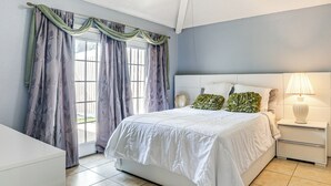 A bedroom with a bed, nightstand, lamp, and curtains. - Private Heated Pool: Quiet Getaway in San Antonio (San Antonio)