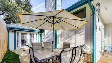 A patio with a table and chairs, an umbrella, and a small stool.