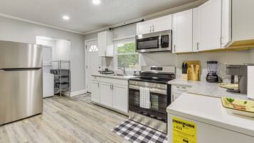 A modern kitchen with white cabinets, stainless steel appliances, and a checkered floor mat.