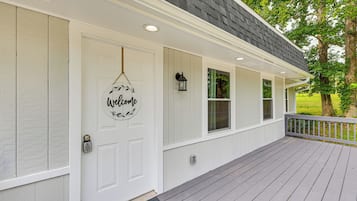 A white house with a gray porch and a welcome sign.