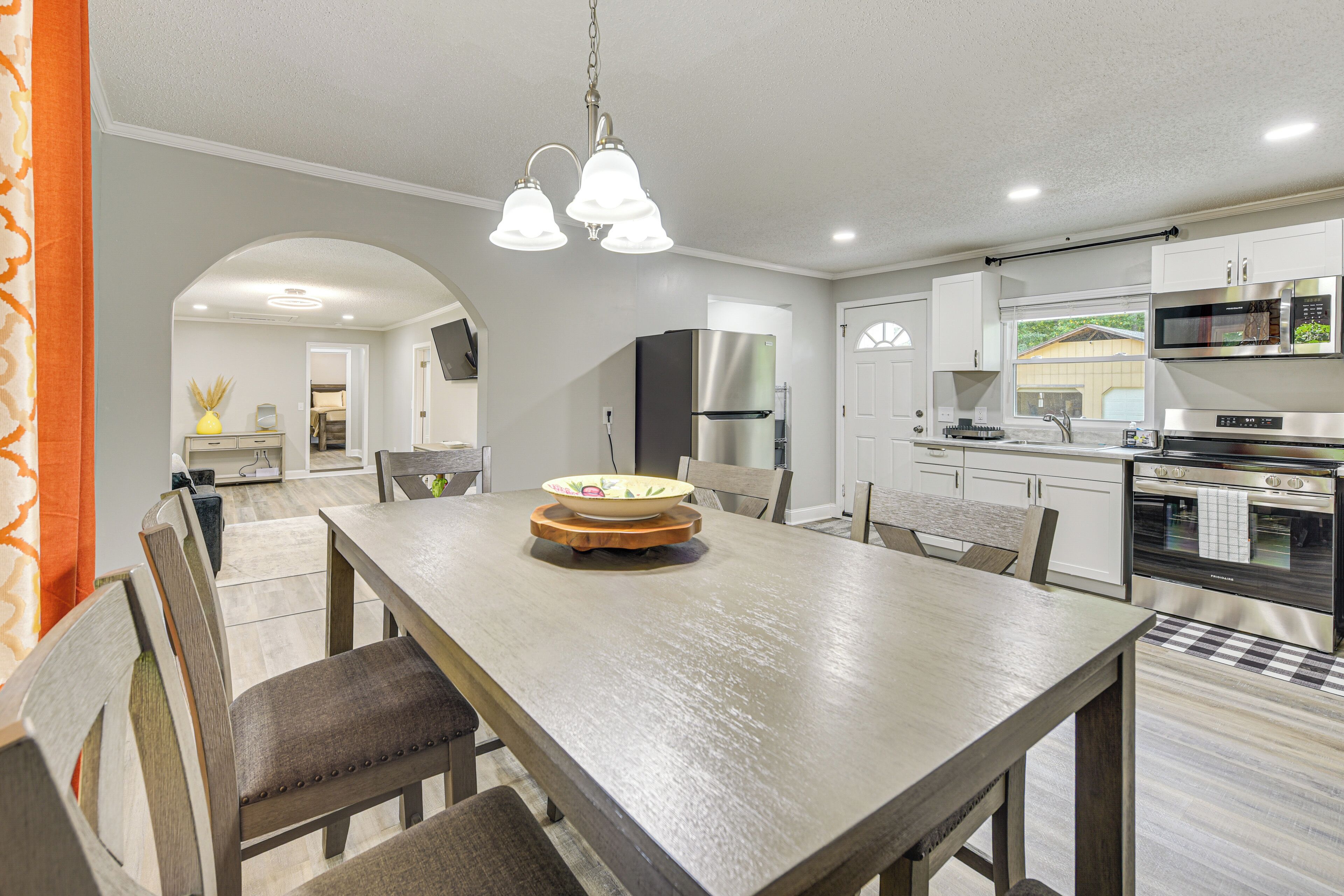 A modern kitchen with white cabinets, stainless steel appliances, and a wooden dining table with chairs.