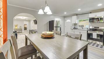 A modern kitchen with white cabinets, stainless steel appliances, and a wooden dining table with chairs.