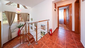 Una escalera con barandilla metálica, un extintor rojo y una planta en maceta.