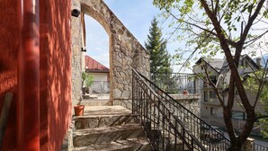 Una escalera de piedra con barandilla de metal que conduce a un edificio de fachada pétrea.