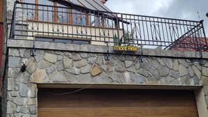 Fachada de piedra con puerta de garaje, un balcón con barandillas de metal y un letrero que dice “Mont Arte”.