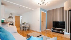 A modern living room with a sofa, TV, and wooden flooring.
