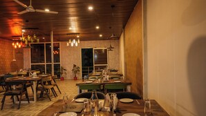 Un restaurante con suelo de madera, varias mesas, sillas e iluminación colgante.