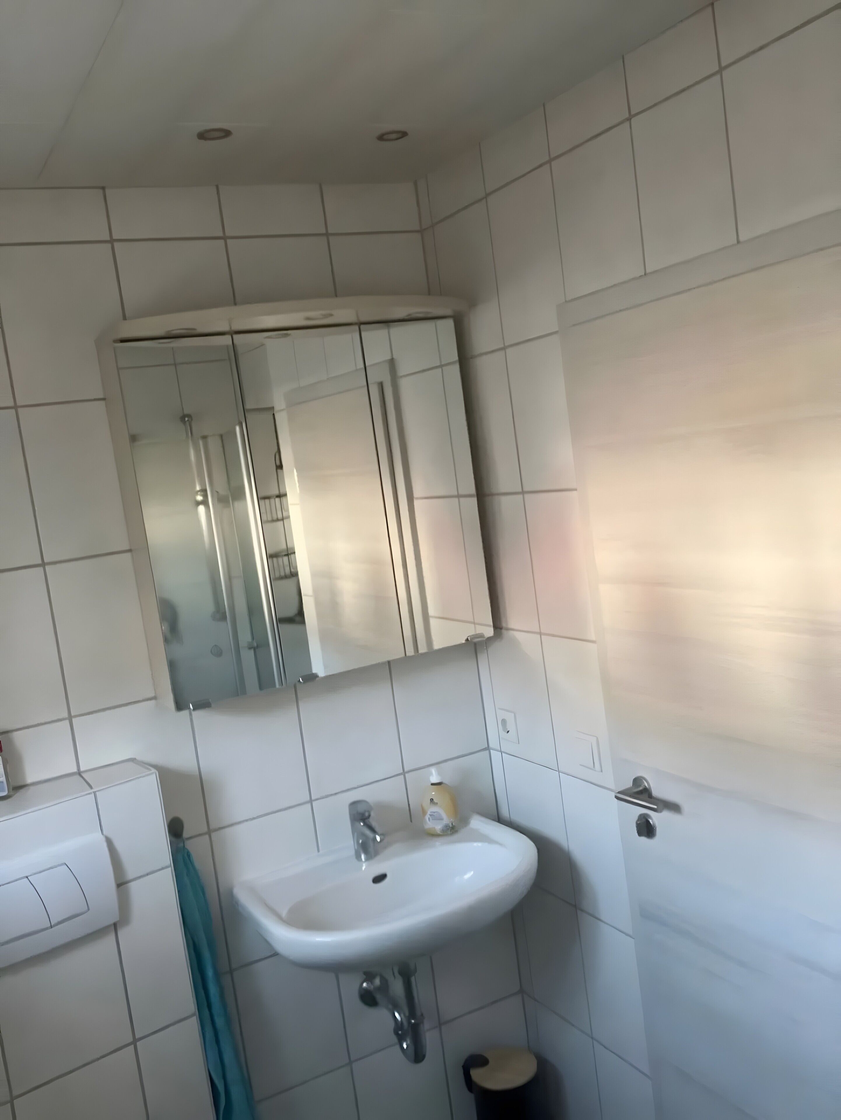Un baño con un lavabo blanco, un espejo encima y una toalla colgada en la pared.