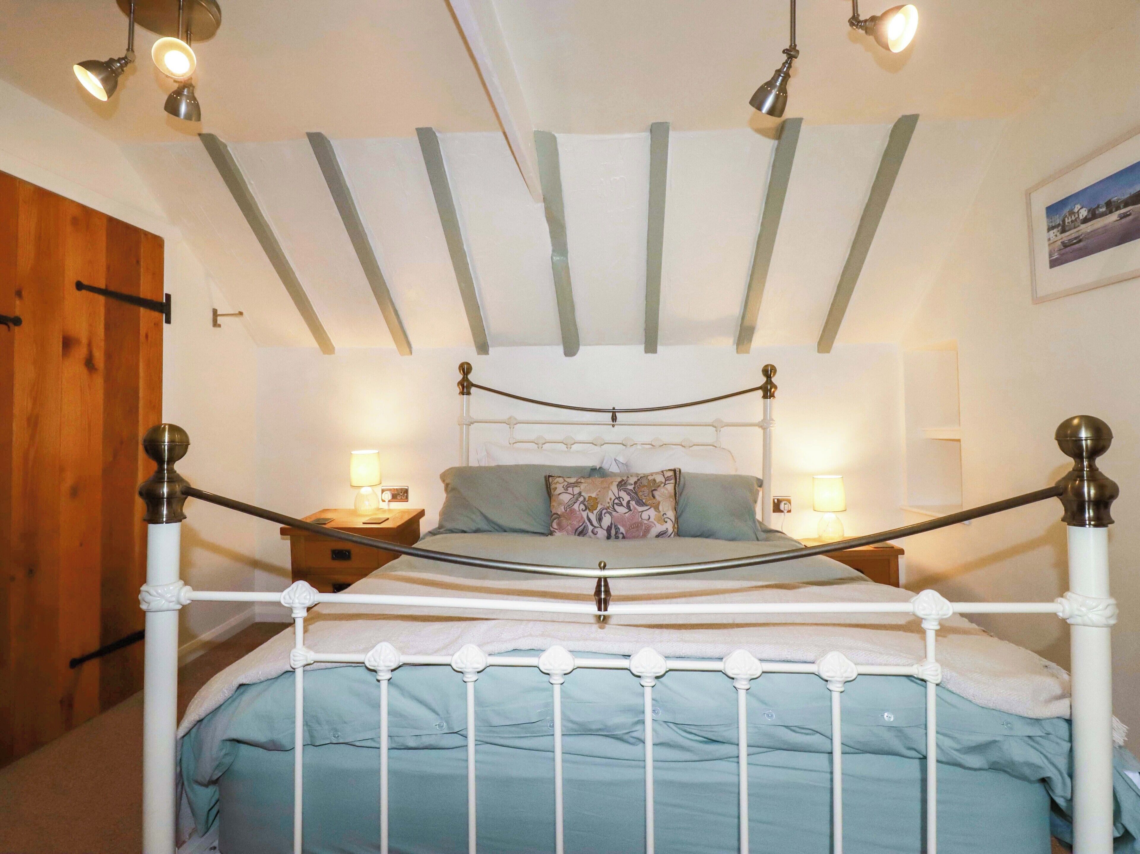 A bedroom with a white metal bed frame, a wooden door, and a ceiling with exposed beams.