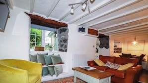A cozy living room with a yellow armchair, a red sofa, and a patterned rug. - Woodview (Looe)