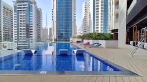 A rooftop swimming pool with clear blue water, surrounded by high-rise buildings. - Manzil - Luxury 2BR w Pool and Burj View (Dubai)