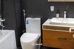 A modern bathroom with a bathtub, toilet, and sink. - Manzil - Luxury 2BR w Pool and Burj View (Dubai)