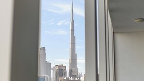 A view of the Burj Khalifa from inside a building, with other high-rise buildings in the background. - Manzil - Luxury 2BR w Pool and Burj View (Dubai)