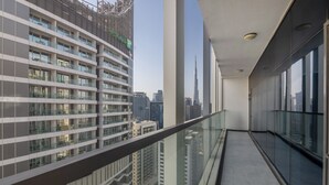 A high-rise building with a balcony overlooking a cityscape. - Manzil - Luxury 2BR w Pool and Burj View (Dubai)
