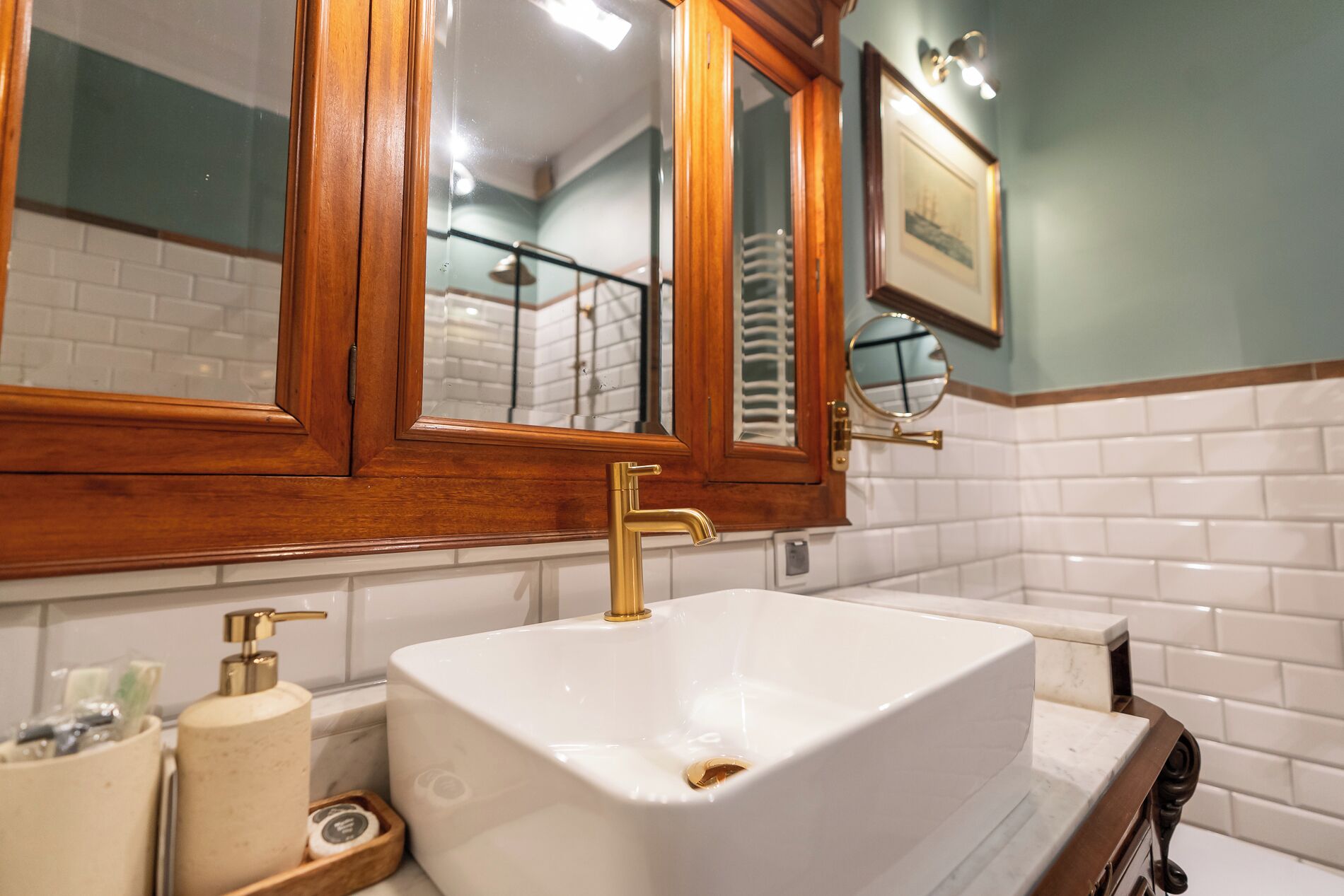 Un bany amb un lavabo blanc, armaris de fusta i un mirall sobre el lavabo.