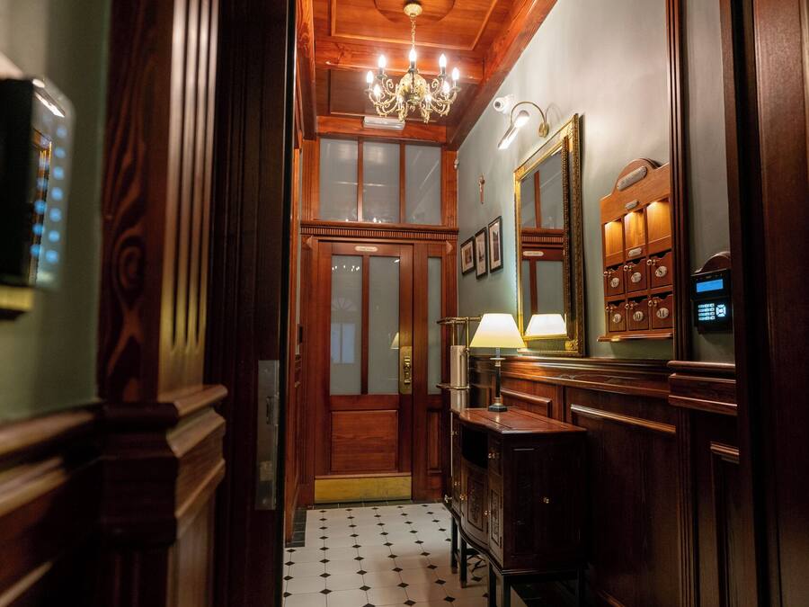 A hallway with a wooden door, a mirror, a clock, and a digital display.