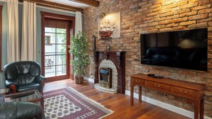 Una sala de estar con pared de ladrillo, chimenea, televisor y mobiliario de cuero.