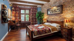 Un dormitorio con cama de madera, un escritorio con un globo terráqueo, una silla, una ventana con cortinas, una planta y una pared de ladrillo con espejo y decoración.