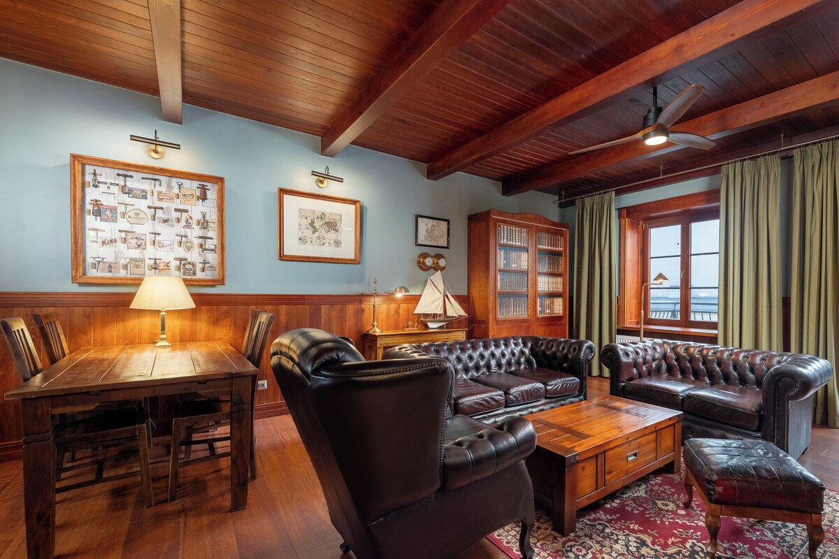 Un salón tradicional con techo de madera, sofás de cuero, una mesa de centro de madera y una estantería.