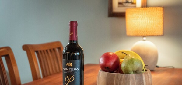 A bottle of Primitivo wine, a wooden bowl with fruits, and a sign for Old House Apartments. - Old House Apartments 2 Poznań (Poznań)