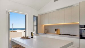Una cucina moderna con una grande isola, mobili bianchi e vista sulla spiaggia.