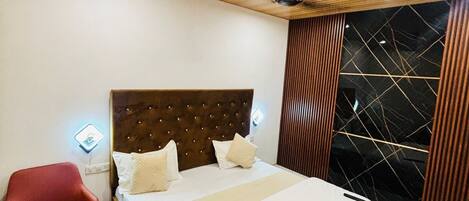 A bedroom with a wooden ceiling, a bed with white linens, a red chair, and a black and white patterned wall.